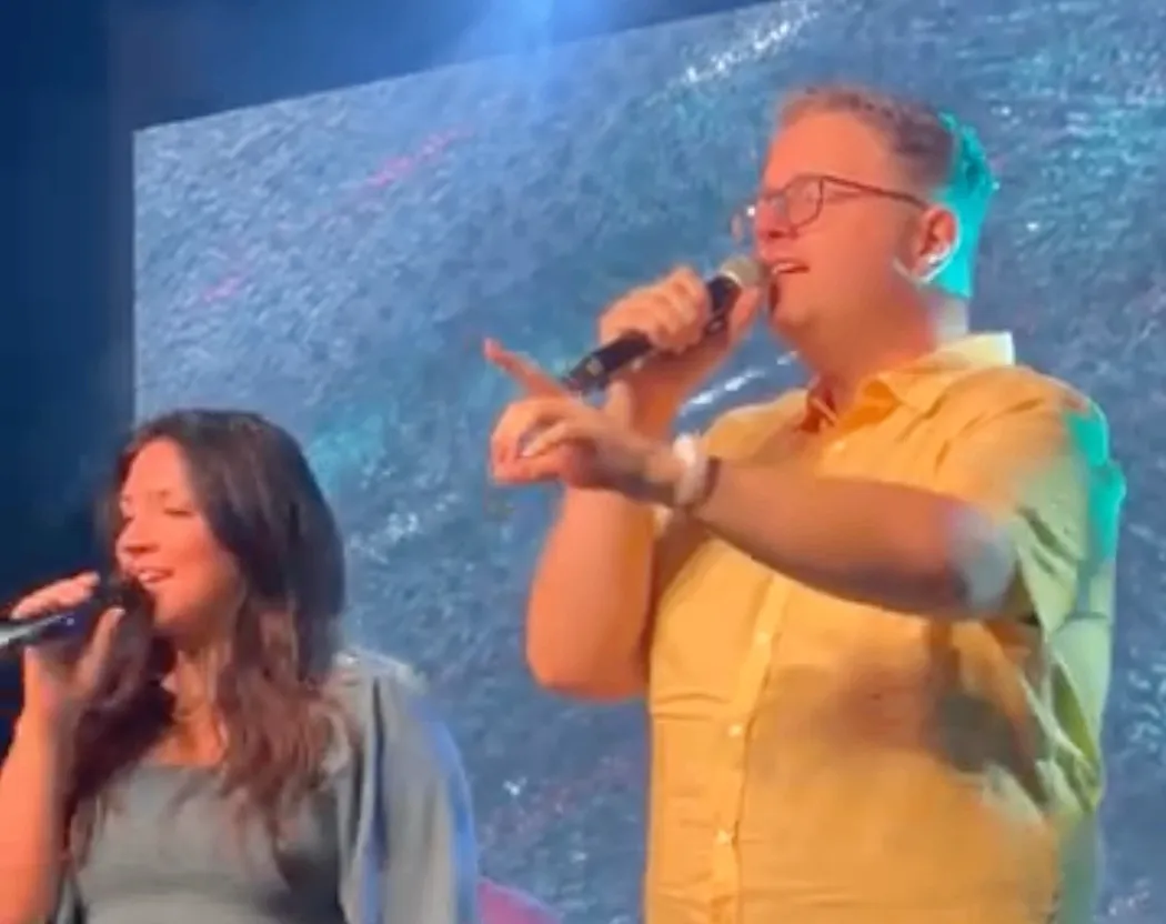 Josh Anders leading worship on stage beside his wife