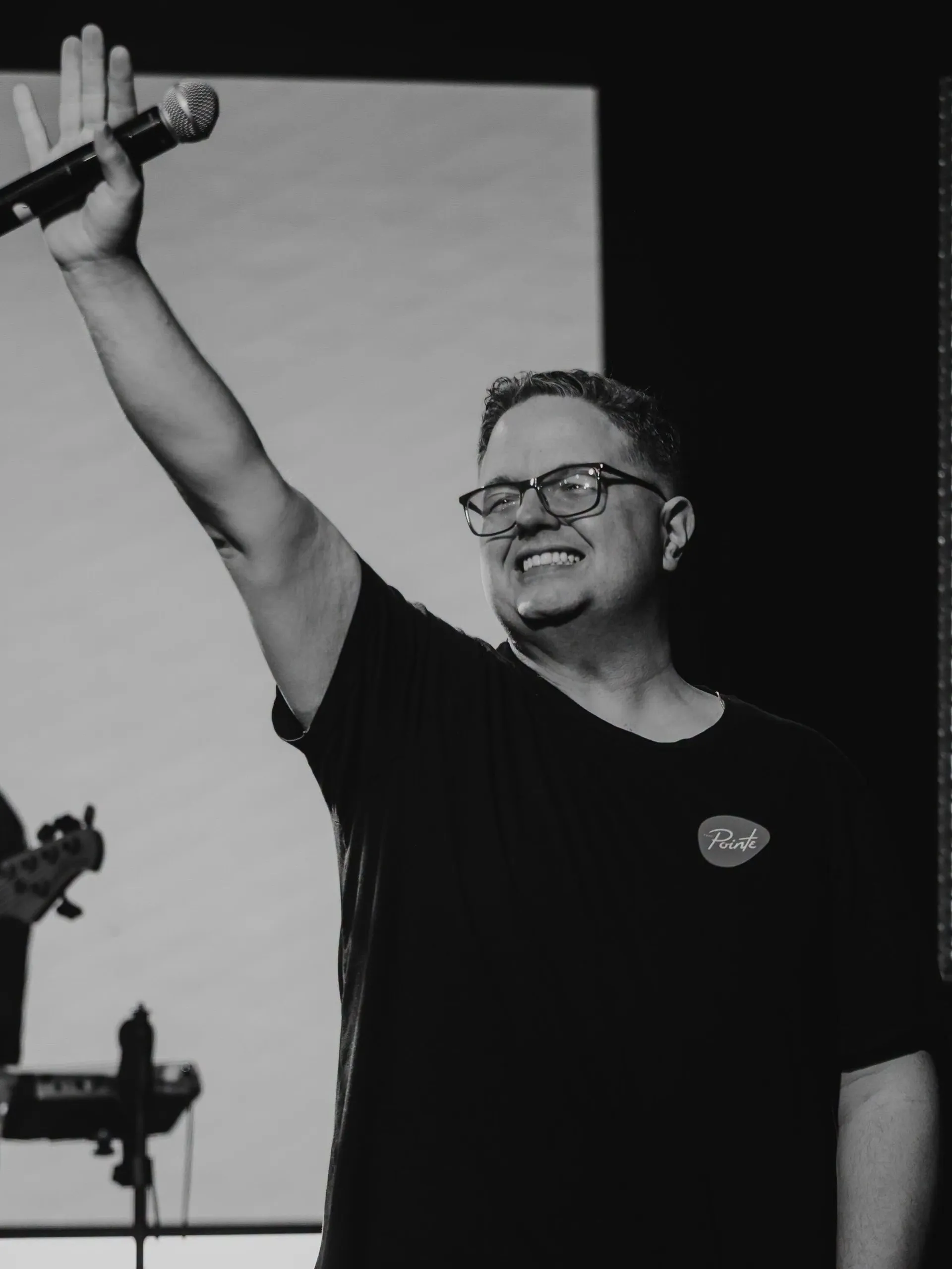 Josh Anders raising his hand and microphone while leading worship