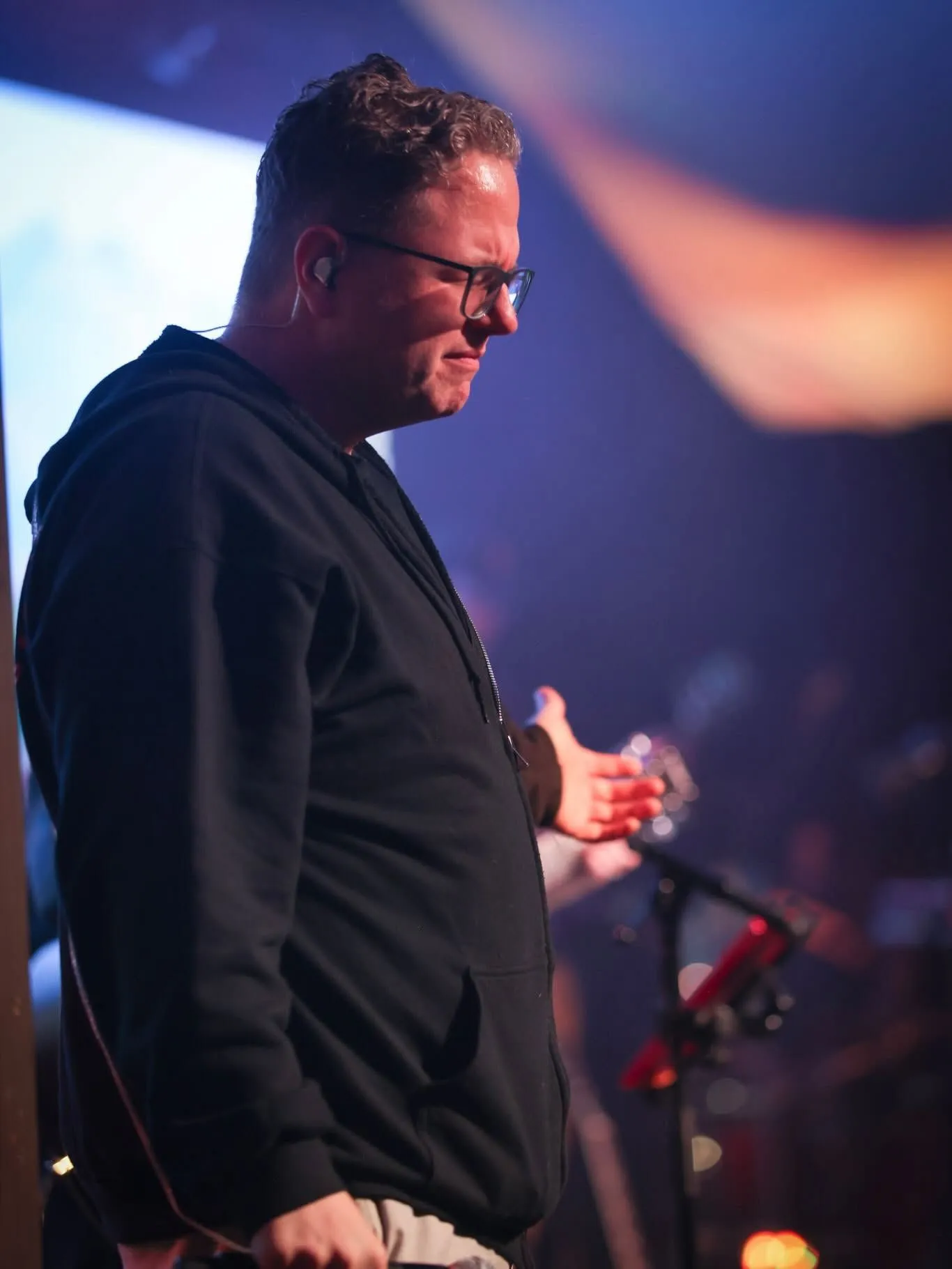 Josh Anders in a black hoodie beside a worship console